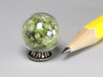 Tiny glass orb filled with peridot chips