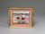 Framed artwork of two children on a beach with a gold frame.