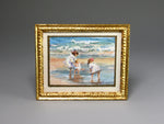 Framed miniature artwork of children playing on a beach with a gold frame.