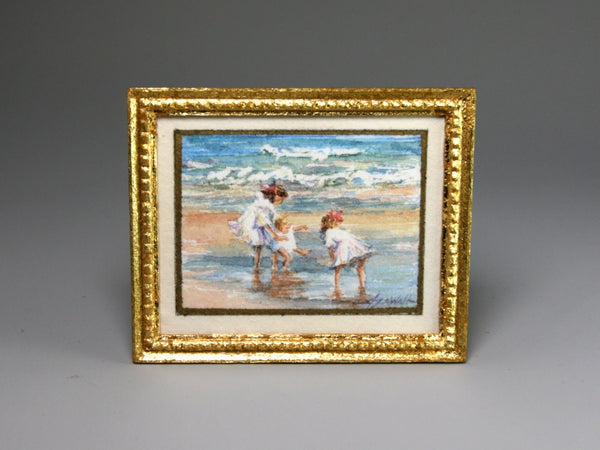 Framed miniature artwork of children playing on a beach with a gold frame.